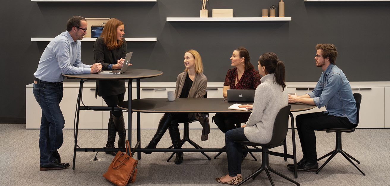 Image of colleagues chatting at multi-tiered desk